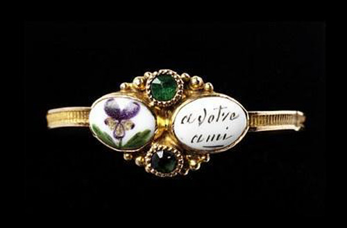 Золотое кольцо со вставками в виде зелёных гранатов. Эмалевый рисунок фиалки как символа нежности и надпись -a votre ami- (-вашему другу-) являются явным признаком романтизма. Изготовлено в Англии в 1830-е годы.